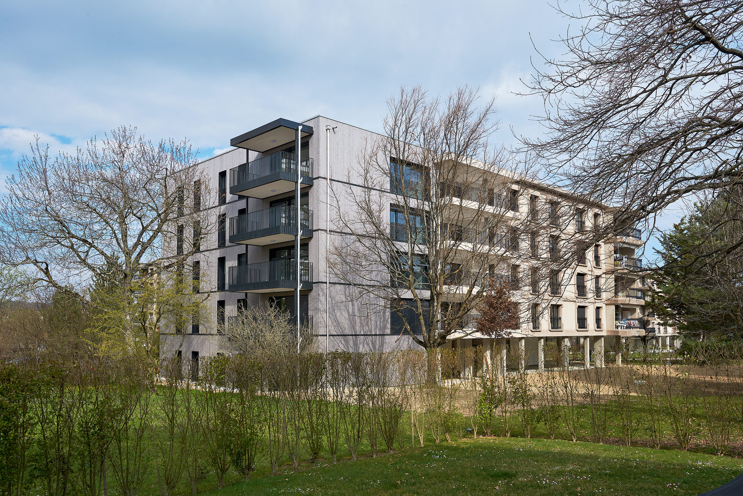Rénovation énergétique Minergie d'un immeuble locatif des années 80 à Fribourg avec extension en bois