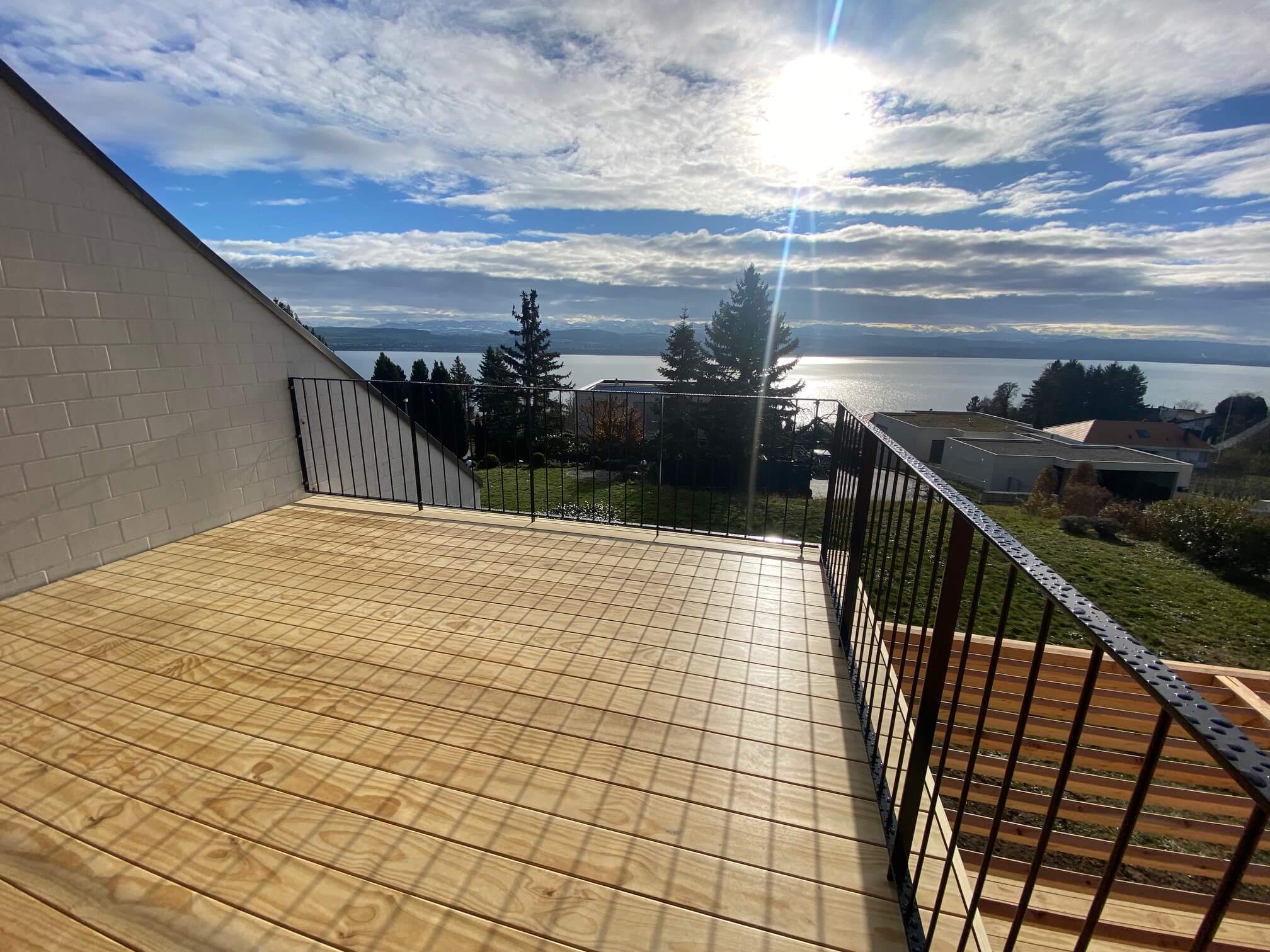 Rénovation Minergie d'une maison jumelée à Lugnorre: terrasse bois avec vue sur le lac de Morat
